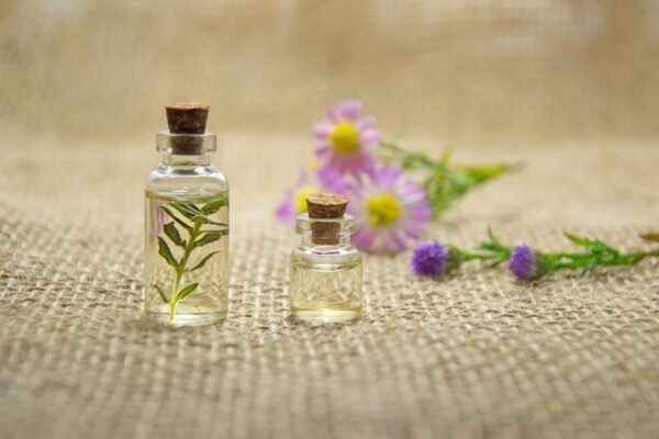 Glass bottles of essential oils with fresh flowers